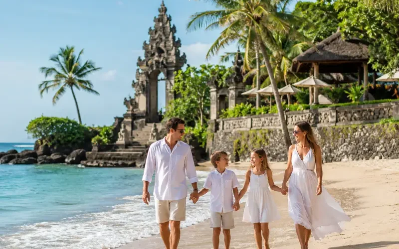 Family enjoying Bali beach with turquoise sea, golden sand, palm trees, and Balinese resort architecture.