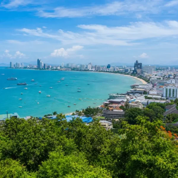 Pattaya Bay coastline with turquoise sea, beachfront skyline and tropical greenery in bright daytime