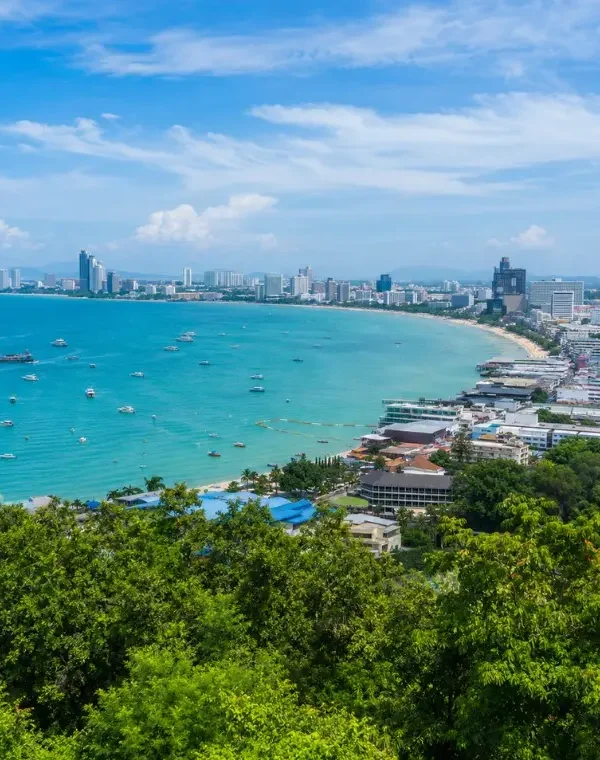 Pattaya Bay coastline with turquoise sea, beachfront skyline and tropical greenery in bright daytime