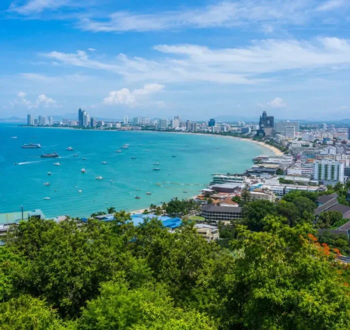 Pattaya Bay coastline with turquoise sea, beachfront skyline and tropical greenery in bright daytime