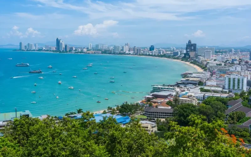 Pattaya Bay coastline with turquoise sea, beachfront skyline and tropical greenery in bright daytime