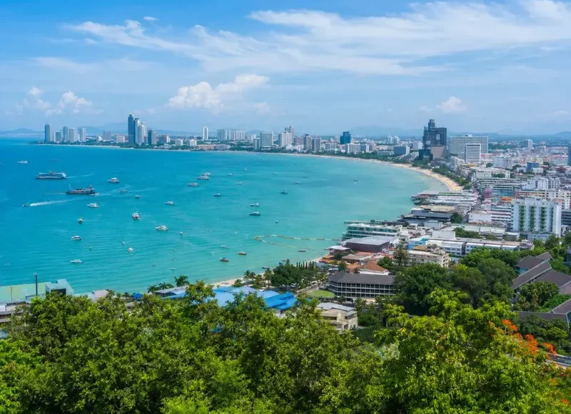 Pattaya Bay coastline with turquoise sea, beachfront skyline and tropical greenery in bright daytime