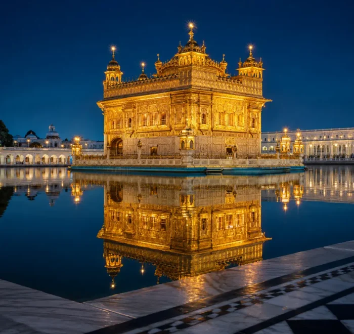 Golden Temple in Amritsar glowing at night with golden lights, calm water reflection, marble walkway, and a luxury spiritual travel atmosphere.