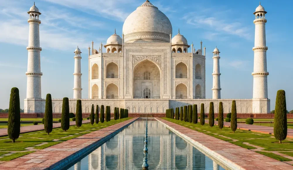 Taj Mahal in Agra with white marble architecture, blue sky, landscaped gardens, and a clear reflection pool, shown without people.