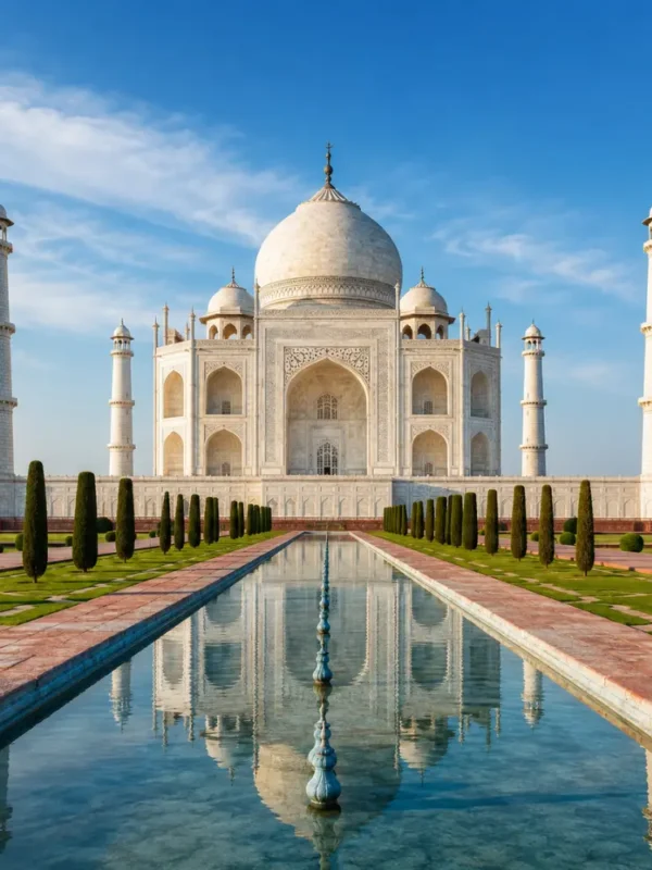 Taj Mahal in Agra with white marble architecture, blue sky, landscaped gardens, and a clear reflection pool, shown without people.