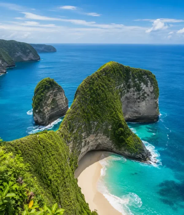 Nusa Penida, Bali with dramatic green cliffs, turquoise sea, white sandy beach, and clear blue sky in bright daylight.