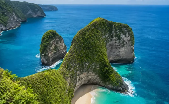 Nusa Penida, Bali with dramatic green cliffs, turquoise sea, white sandy beach, and clear blue sky in bright daylight.