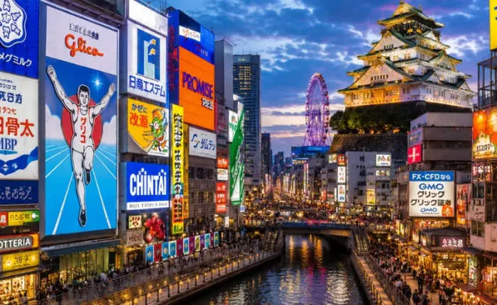 Vibrant Osaka city view with Dotonbori canal, neon streets, river boat, and Osaka Castle in the background.