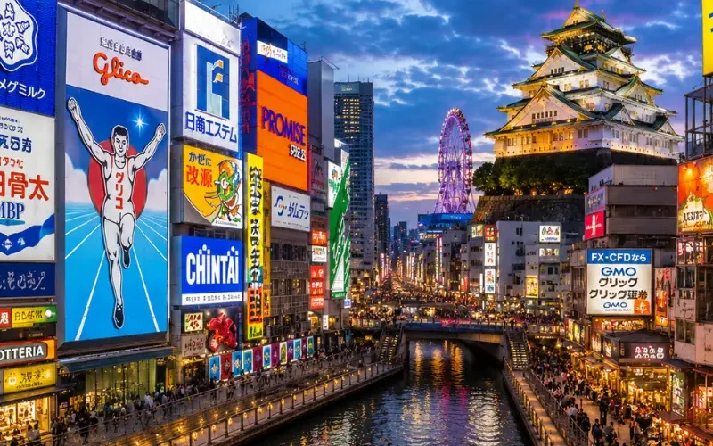 Vibrant Osaka city view with Dotonbori canal, neon streets, river boat, and Osaka Castle in the background.