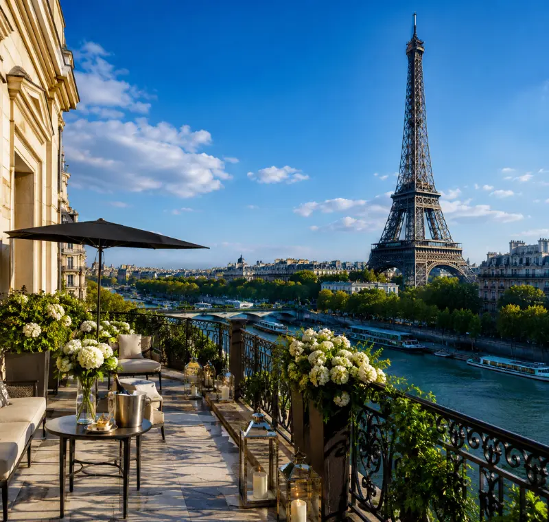 Luxury Paris terrace overlooking the Eiffel Tower, Seine River, elegant balcony seating, flowers, and clear blue sky.