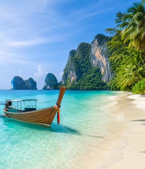 Phuket Island beach with turquoise water, long-tail boat, white sand and tropical limestone cliffs