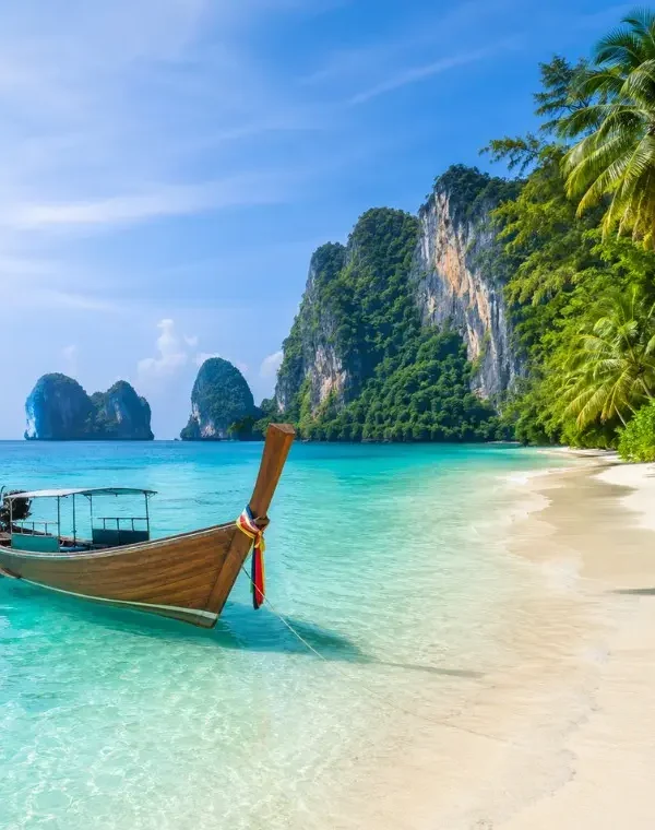 Phuket Island beach with turquoise water, long-tail boat, white sand and tropical limestone cliffs
