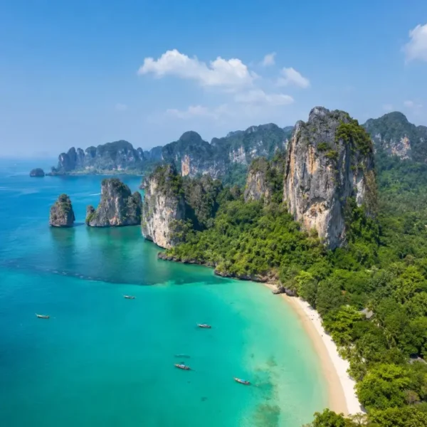 Krabi coastline with turquoise sea, limestone cliffs, white sand beach and tropical greenery in daylight