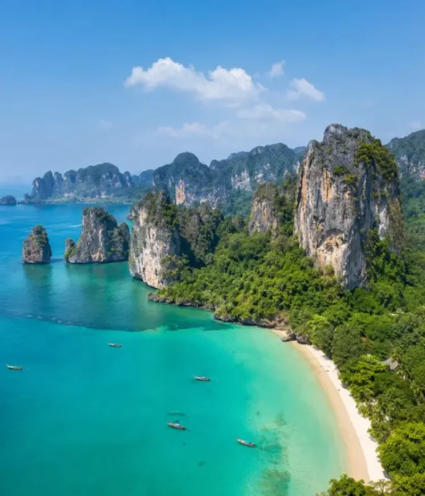 Krabi coastline with turquoise sea, limestone cliffs, white sand beach and tropical greenery in daylight