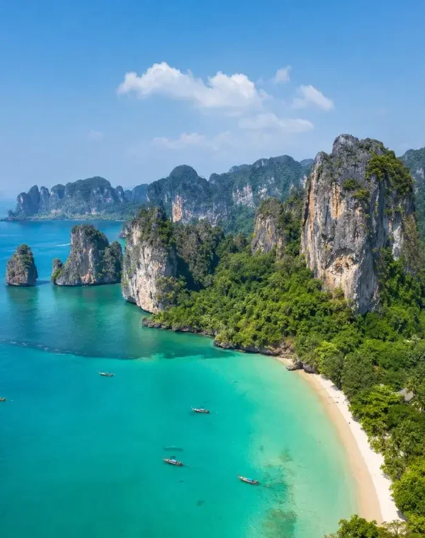 Krabi coastline with turquoise sea, limestone cliffs, white sand beach and tropical greenery in daylight