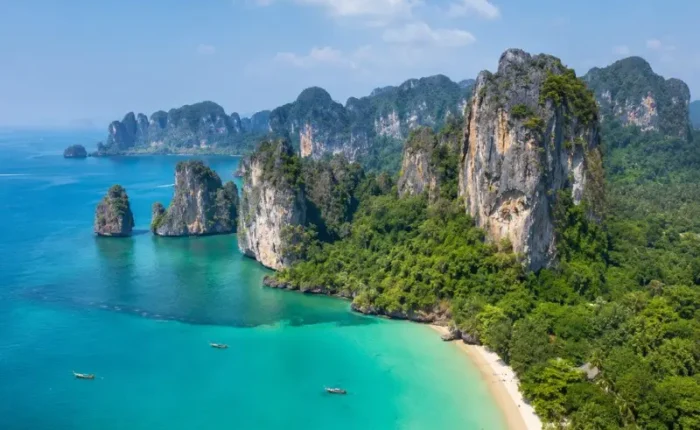 Krabi coastline with turquoise sea, limestone cliffs, white sand beach and tropical greenery in daylight