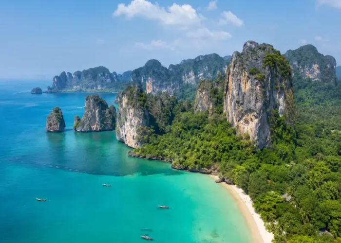 Krabi coastline with turquoise sea, limestone cliffs, white sand beach and tropical greenery in daylight