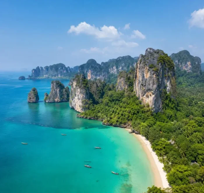 Krabi coastline with turquoise sea, limestone cliffs, white sand beach and tropical greenery in daylight