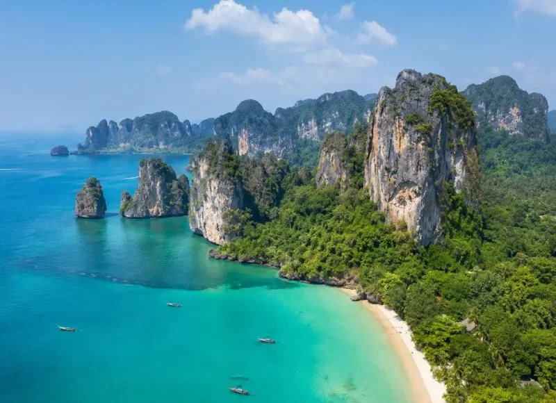 Krabi coastline with turquoise sea, limestone cliffs, white sand beach and tropical greenery in daylight