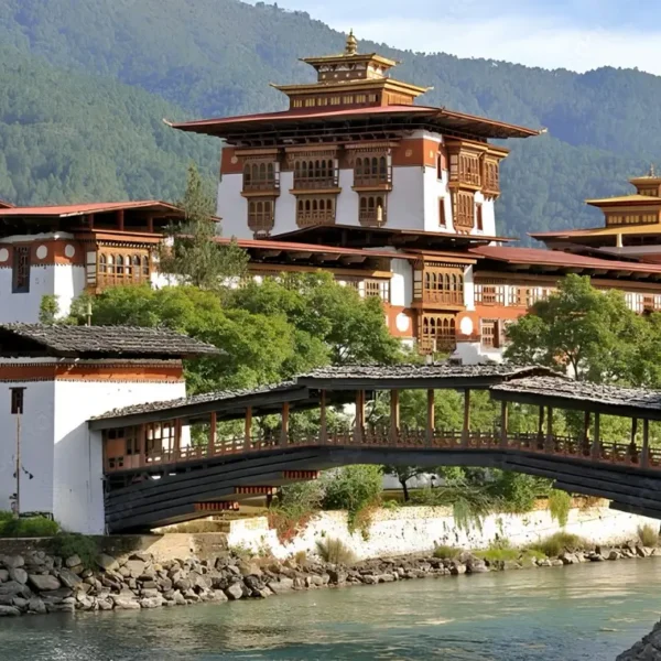 Punakha Dzong in Bhutan with traditional bridge, riverside architecture, forested mountains, and calm water.