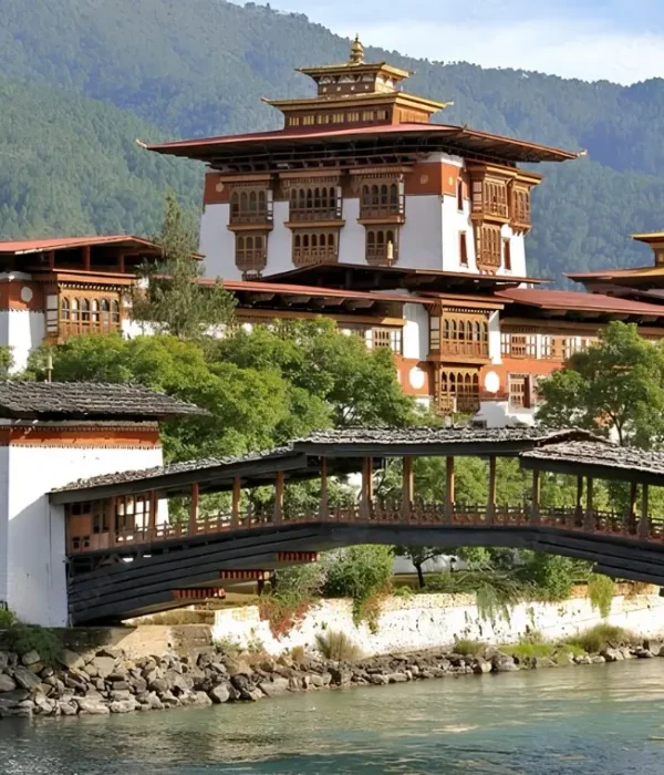 Punakha Dzong in Bhutan with traditional bridge, riverside architecture, forested mountains, and calm water.