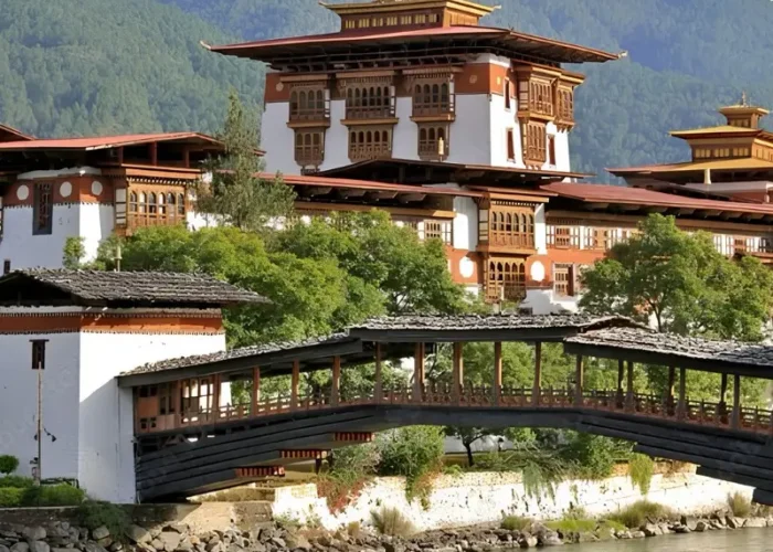 Punakha Dzong in Bhutan with traditional bridge, riverside architecture, forested mountains, and calm water.