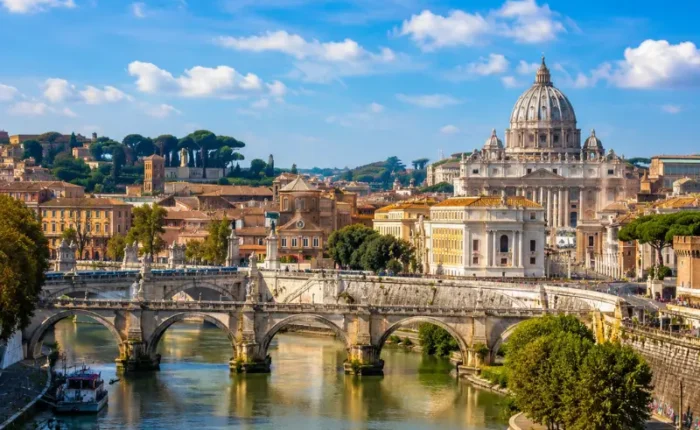 Rome skyline with St. Peter’s Basilica, historic bridge, Tiber River reflections, and warm golden evening light.