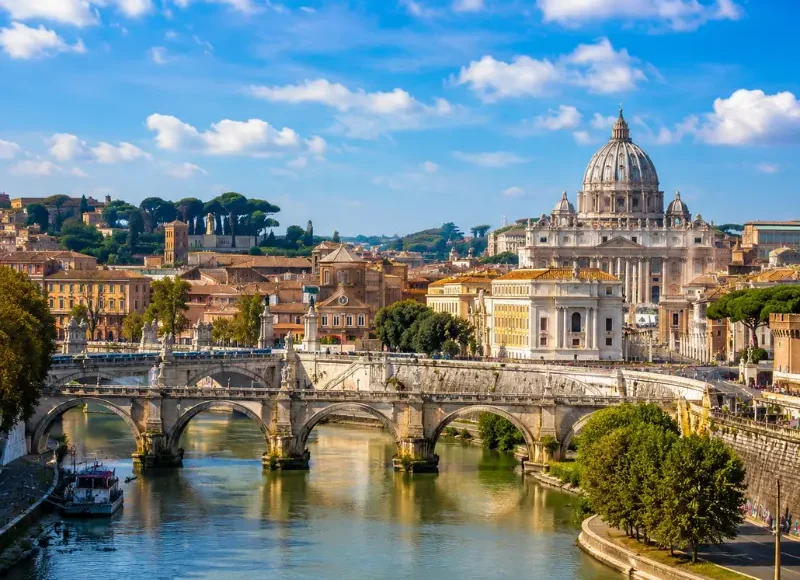 Rome skyline with St. Peter’s Basilica, historic bridge, Tiber River reflections, and warm golden evening light.