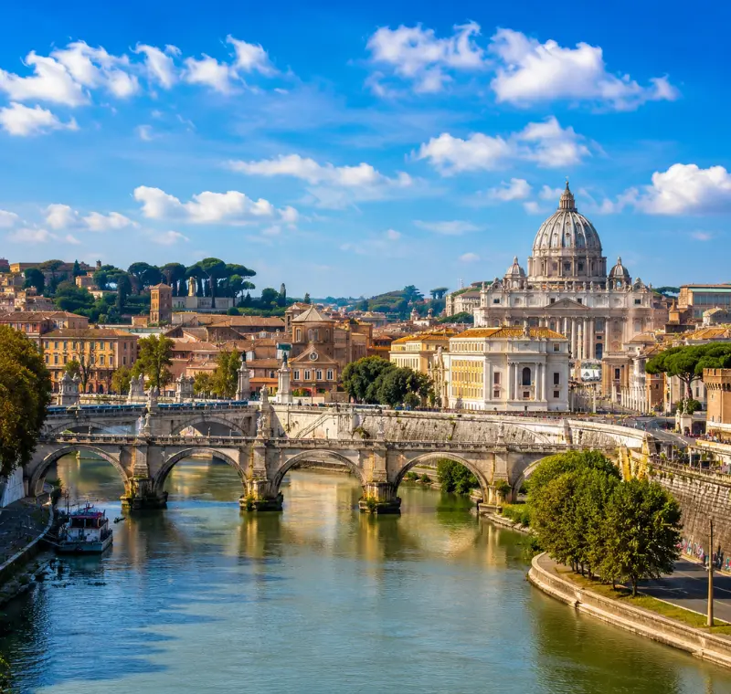 Rome skyline with St. Peter’s Basilica, historic bridge, Tiber River reflections, and warm golden evening light.