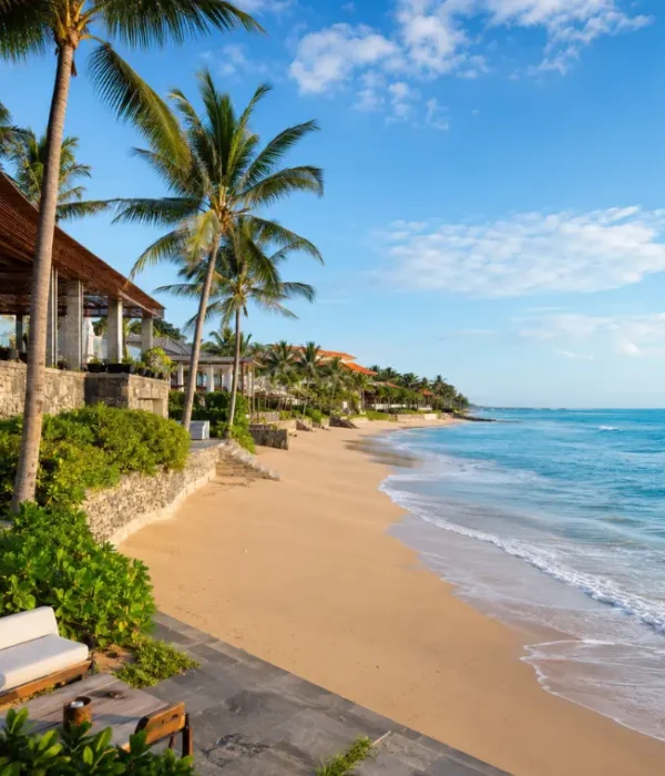 Seminyak, Bali beachfront with golden sand, turquoise sea, swaying palm trees, and luxury seaside villas in clear daylight.