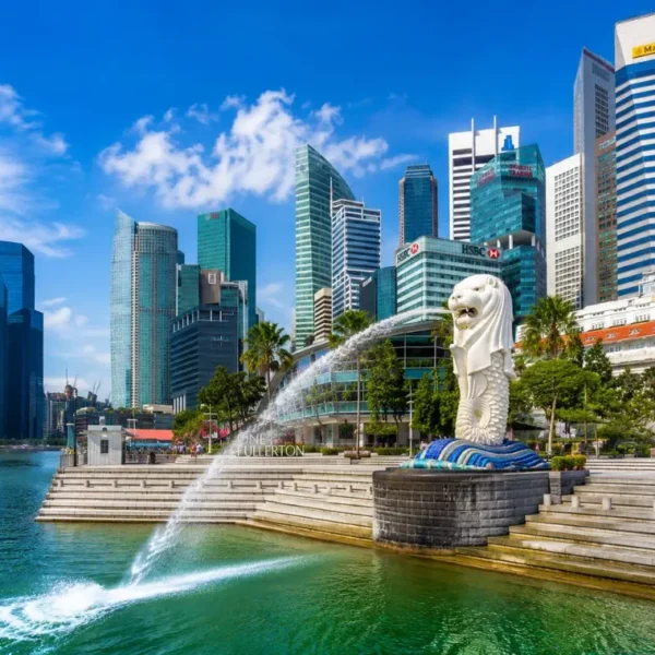 Singapore Merlion at Marina Bay with modern skyline, waterfront promenade and bright blue daytime sky