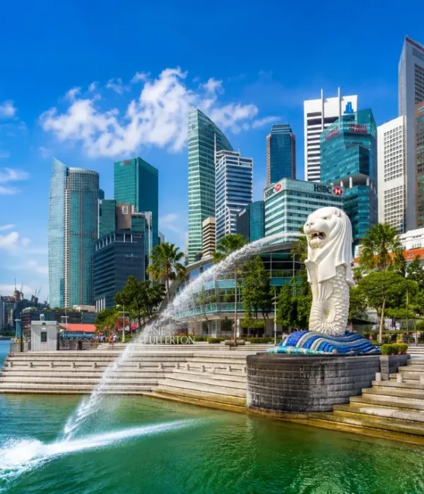 Singapore Merlion at Marina Bay with modern skyline, waterfront promenade and bright blue daytime sky