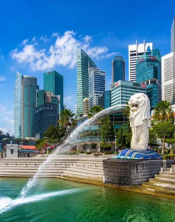 Singapore Merlion at Marina Bay with modern skyline, waterfront promenade and bright blue daytime sky