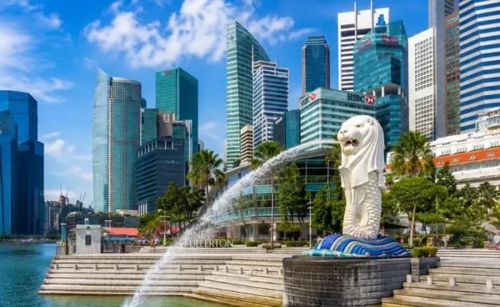 Singapore Merlion at Marina Bay with modern skyline, waterfront promenade and bright blue daytime sky