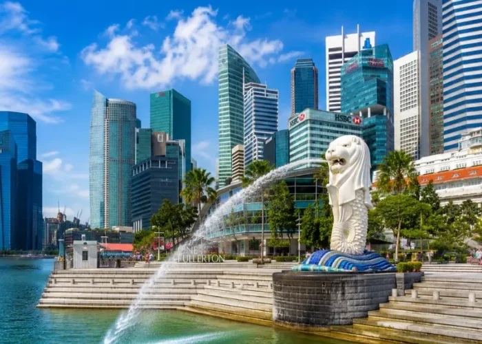 Singapore Merlion at Marina Bay with modern skyline, waterfront promenade and bright blue daytime sky