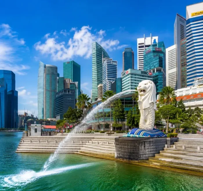 Singapore Merlion at Marina Bay with modern skyline, waterfront promenade and bright blue daytime sky