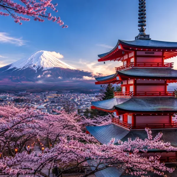 Bright Tokyo view with pink cherry blossom trees, a red temple, and snow-capped Mount Fuji in the background.