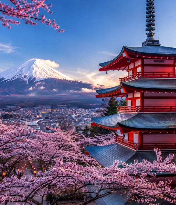 Bright Tokyo view with pink cherry blossom trees, a red temple, and snow-capped Mount Fuji in the background.