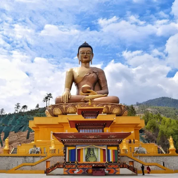 Large Buddha Dordenma statue in Thimphu Bhutan with golden base, forested hills, blue sky, and clouds.