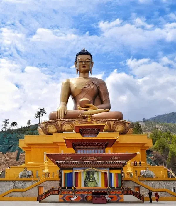 Large Buddha Dordenma statue in Thimphu Bhutan with golden base, forested hills, blue sky, and clouds.