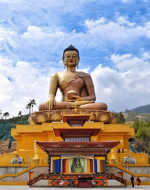 Large Buddha Dordenma statue in Thimphu Bhutan with golden base, forested hills, blue sky, and clouds.