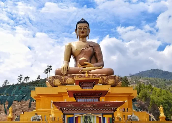 Large Buddha Dordenma statue in Thimphu Bhutan with golden base, forested hills, blue sky, and clouds.