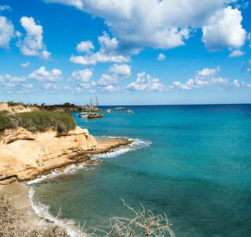 Vast beach with golden cliffs and turquoise waters under a partly cloudy sky, ideal for India beach holiday tours and scenic travel experiences.