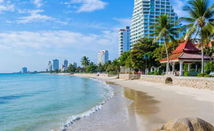 Hua Hin Beach Thailand with calm blue sea, soft sandy shore, luxury resorts, palm trees, and bright morning atmosphere.
