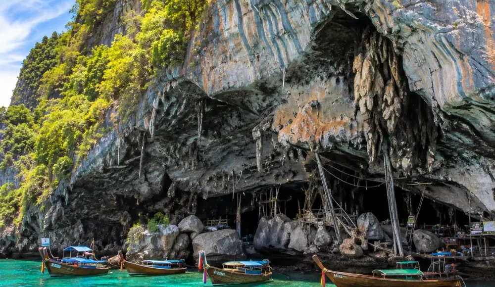 Phi Phi Viking Cave Thailand with limestone cliffs, turquoise sea, boat views, and bright morning island atmosphere.