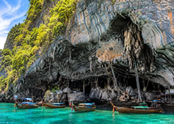 Phi Phi Viking Cave Thailand with limestone cliffs, turquoise sea, boat views, and bright morning island atmosphere.
