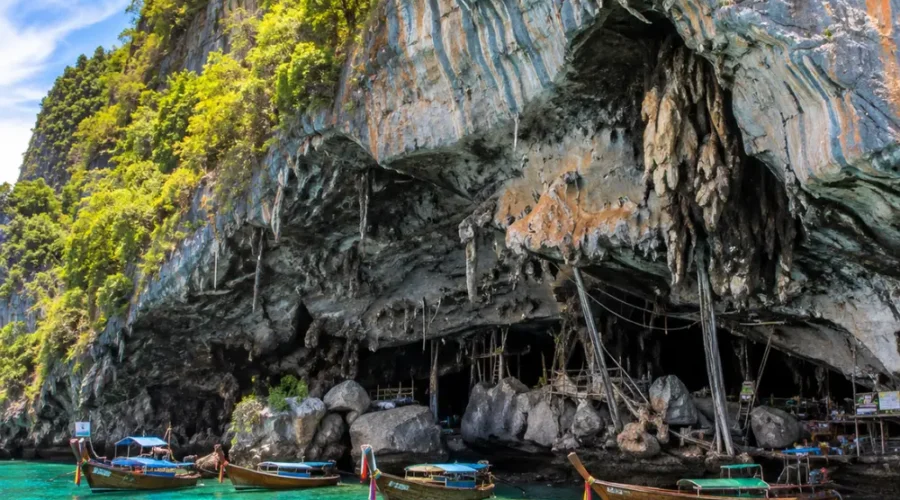 Phi Phi Viking Cave Thailand with limestone cliffs, turquoise sea, boat views, and bright morning island atmosphere.