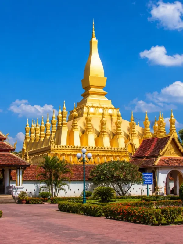 Vientiane Laos with Pha That Luang golden stupa, peaceful gardens, blue sky, and a premium cultural travel atmosphere.