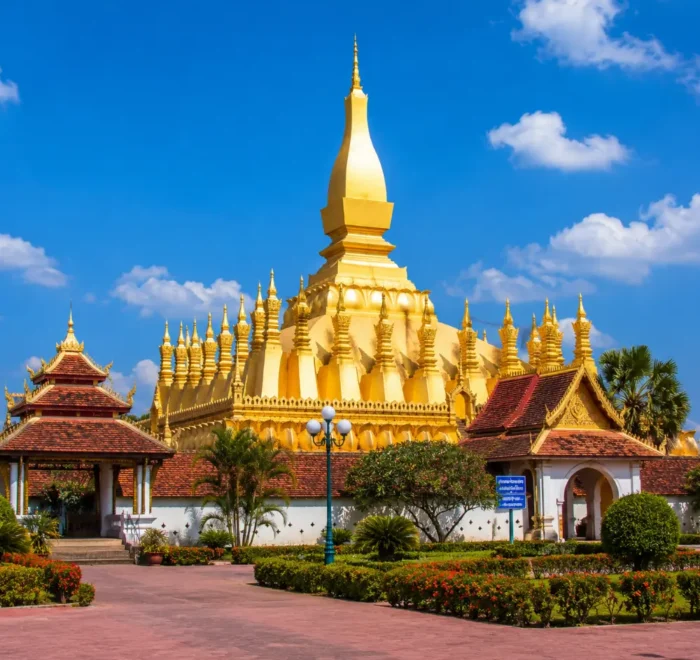 Vientiane Laos with Pha That Luang golden stupa, peaceful gardens, blue sky, and a premium cultural travel atmosphere.