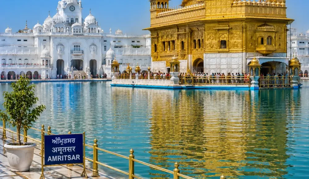 Amritsar Golden Temple with sacred pool reflections, Sikh architecture and clear morning daylight in Punjab.